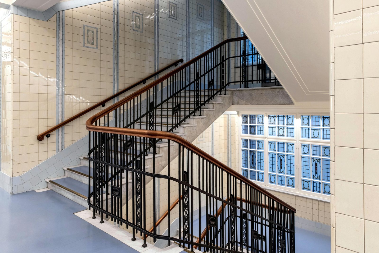 Spacious stairwell in historic Hamburg building with intricate railings and tiled walls.